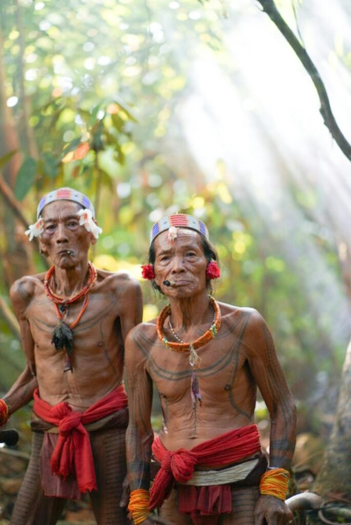 Two Minangkabau men in traditional attire, standing in a lush West Sumatra rainforest.