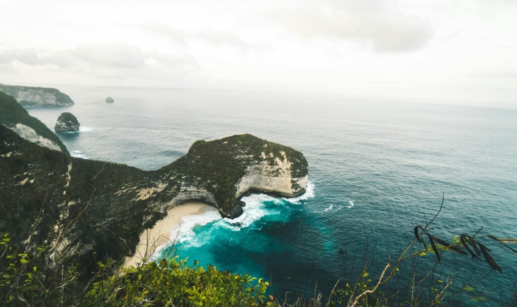 Stunning aerial view over Kelingking Beach on Nusa Penida, showcasing cliffs and turquoise ocean waters.